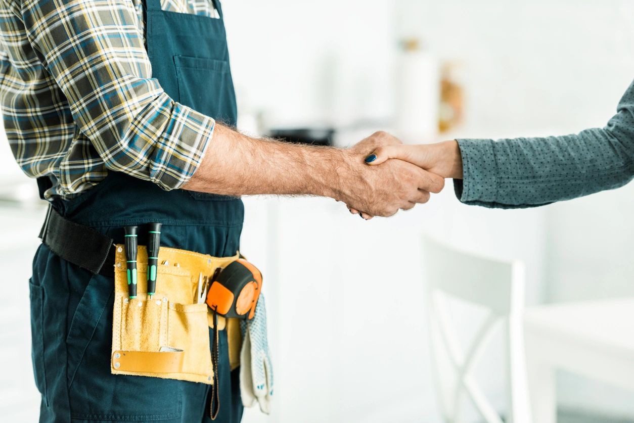 Cropped image of plumber and client shaking hands in kitchen